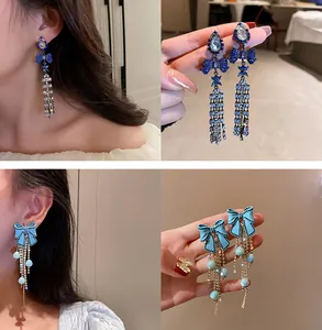 Détail des boucles d'oreilles à pampilles papillon en cristal montrant l'effet de portée