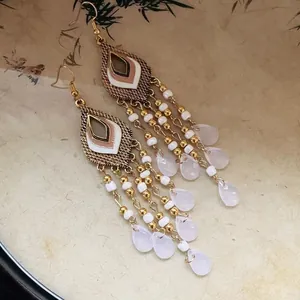 Detailed view of bohemian gold tassel earrings with white beads and teardrop charms