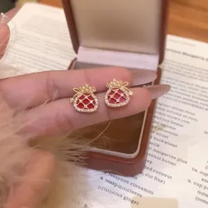 Macro view of exquisite red lucky bag stud earrings with gold plating, zircons, and pearls