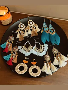 Detailed shot of various bohemian feather and tassel earrings displayed on a black plate.