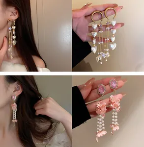 Gros plan de boucles d'oreilles à pompons avec perles cœurs et fleurs de cristal rose.