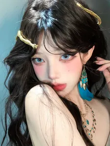 Detailed shot of bohemian style blue feather tassel earrings and vintage gold jewelry on model