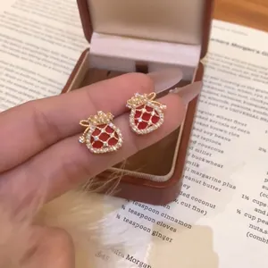 Macro view of exquisite red lucky bag stud earrings with micro-inlaid zircons and pearls