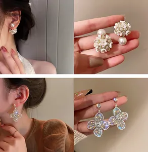 Détail des boucles d'oreilles papillon en cristal et fleurs de perles sur modèle