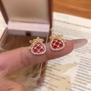 Close-up detail showing red lucky bag stud earrings with pearls and zircon insets