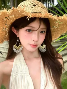Model wearing elegant Bohemian drop earrings with white shell discs and gold frame