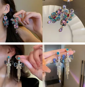 Détails des boucles d'oreilles en cristal papillon et pompons en strass cœur bleu.