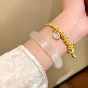 Macro view of translucent resin bangle and gold beaded bracelet on wrist