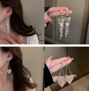 Détails rapprochés de boucles d'oreilles en cœur scintillant et glands de perles ornés