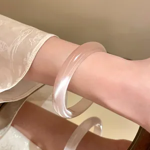 Detailed close-up view of an elegant translucent pink resin bangle worn on a wrist