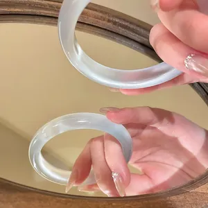 Detailed macro view of a translucent ice-clear resin bangle reflecting in a mirror surface