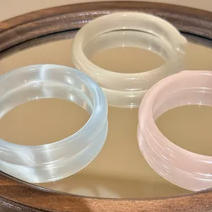 Detailed macro view of translucent ice-clear resin round bracelets in three soft colors