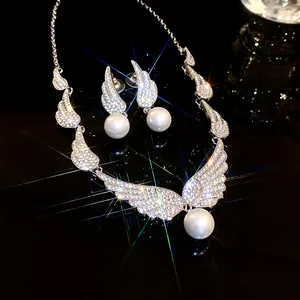Close-up of elegant sparkling rhinestone wing and pearl jewelry set on black background