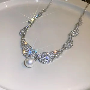 Elegant angel wing necklace adorned with sparkling rhinestones and a lustrous pearl drop.
