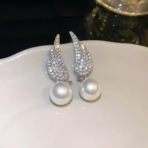 Detailed view of elegant silver wing earrings with sparkling crystals and pearls