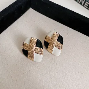 Close-up view of vintage black and white enamel stud earrings with a gold texture