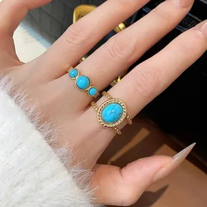 Primer plano de elegantes anillos abiertos bañados en oro de 18k con piedras turquesas