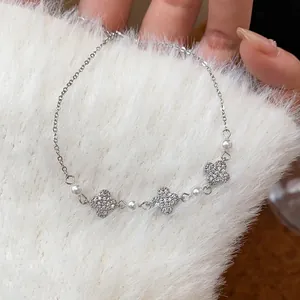 Close-up of silver-tone bracelet with pavé zircon flowers and elegant white pearls detail