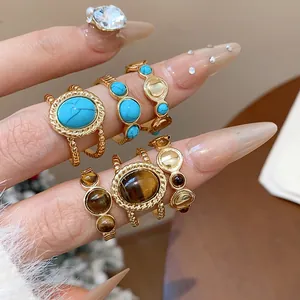 Primer plano de anillos vintage bañados en oro 18k con turquesa y ojo de tigre