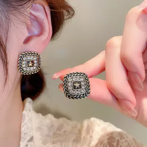 Close-up of vintage square star stud earrings with rhinestone detailing and star motif