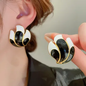 Detailed view of vintage black and white enamel stud earrings worn and held by hand.