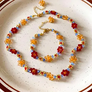 Primo piano di set collana e bracciale con fiori di perline colorate su un piatto