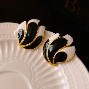 Close-up detail of vintage black and white enamel stud earrings on a ceramic plate