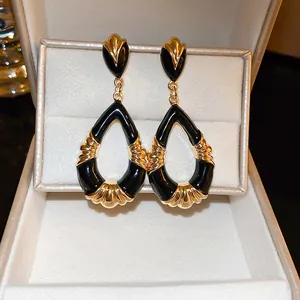Close-up of elegant vintage black and gold teardrop earrings presented in a jewelry gift box.