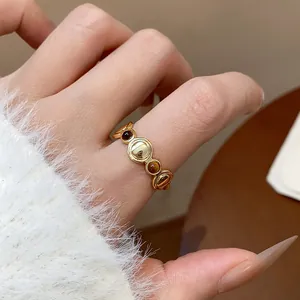 Detalle de cerca de anillo redondo vintage chapado en oro de 18k en mano con suéter blanco