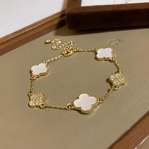 Close-up detail of a gold clover charm bracelet with white acetate and crystal pavé elements