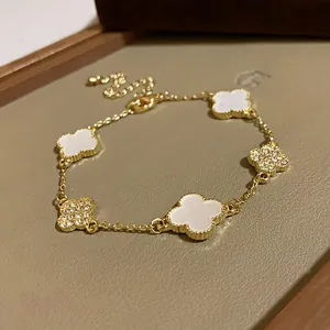 Close-up of gold chain bracelet featuring white acetate and diamond-studded flower motifs.