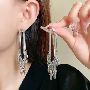 Elegant long silver tassel earrings with leaf-shaped charms shown on a model's ear