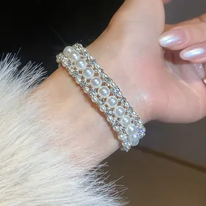 Dettaglio di un braccialetto francese a tre fili di perle e strass indossato al polso.