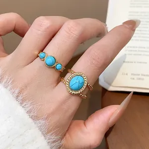 Vista detallada de anillos vintage bañados en oro de 18k con piedras turquesas en la mano
