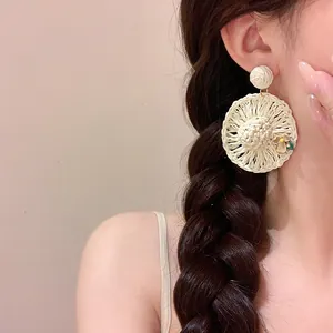 Close-up detail of handcrafted Bohemian raffia woven straw hat earrings with flowers