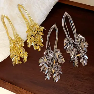 Elegant gold and silver leaf tassel earrings with detailed wheat ear design on wood