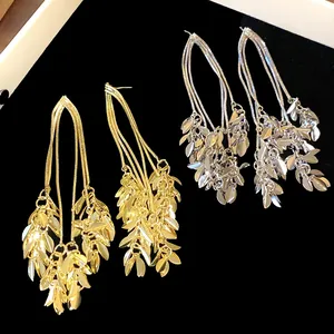 Detailed macro view of elegant gold and silver leaf tassel earrings on black velvet
