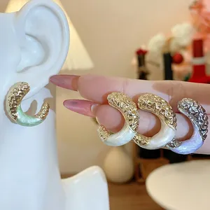 Elegant gold-tone C-shaped hoop earrings with pleated texture and colorful enamel detail.