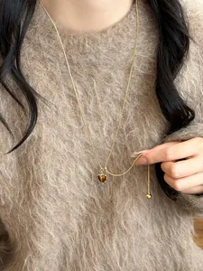 Primo piano di una collana vintage con ciondolo a cuore su un caldo maglione marrone
