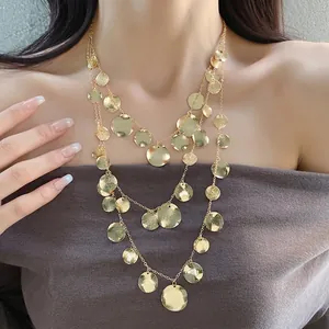 Elegant three-layer gold necklace featuring textured circular disk pendants on a model.
