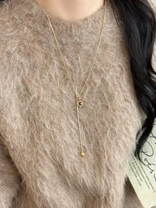 Dettaglio collana con ciondolo a sole vintage con catena a Y dorata su maglione