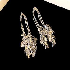 Close-up of silver leaf tassel earrings showing detailed layered metal texture.