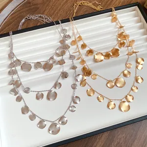 Detailed view of layered necklaces with textured circular charms in gold and silver.