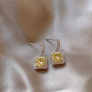 Macro detail showing exquisite square halo earrings with radiant yellow zircon stones