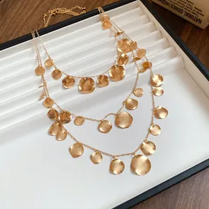Detailed close-up view of triple-layered gold necklace with hammered round metal disc charms