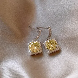Detailed view of elegant square yellow zircon pendant earrings on luxury champagne silk