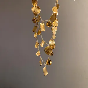 Detailed view of textured golden layered necklace with hanging coin pendants