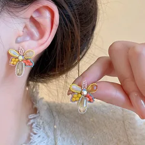 Macro view showing the intricate beadwork and central crystal of the flower earrings detail