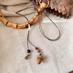 Dettaglio della collana con ciondolo a ghianda in stile etnico e perline di legno.