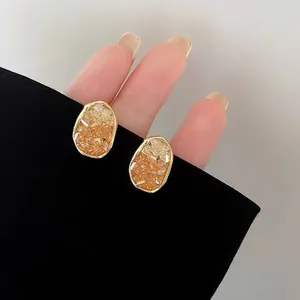 Elegant irregular amber crystal stud earrings with gold-tone metallic borders for women